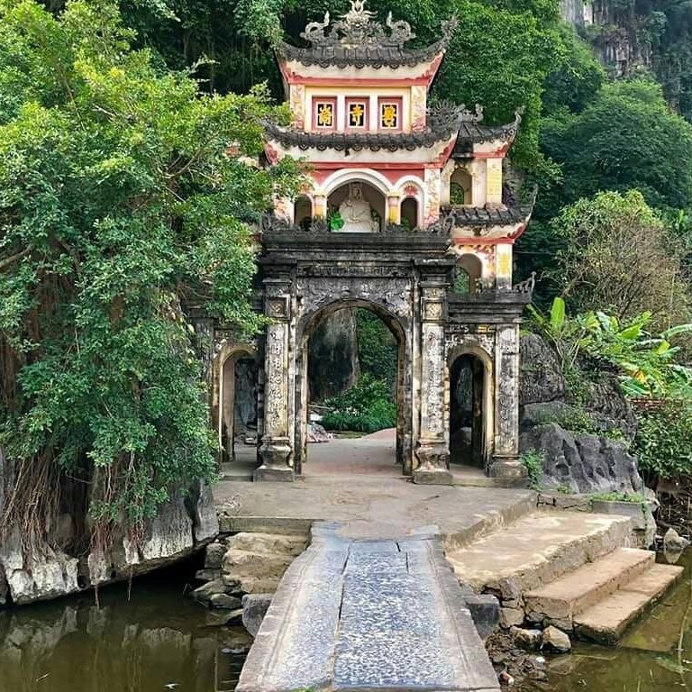 Premium Photo  Lone tourist with traditional vietnamese hat at bich dong  pagoda entrance gate, ninh binh vietnam, buddhist temple set amid jungle  and karst mountain range. traveling alone, keep social distancing.